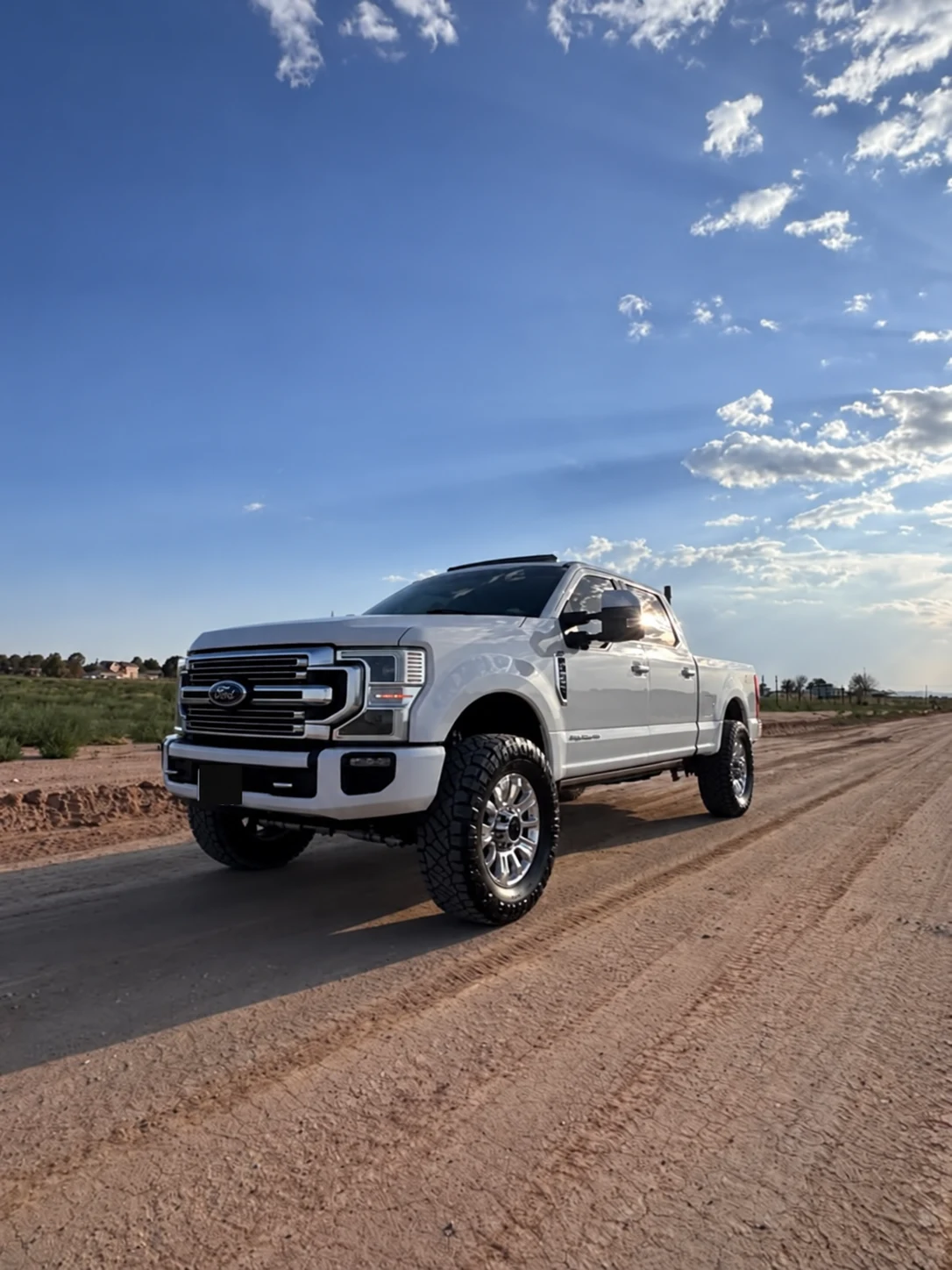 The white 2022 Ford F-350 Limited photographed from the front on a dirt road